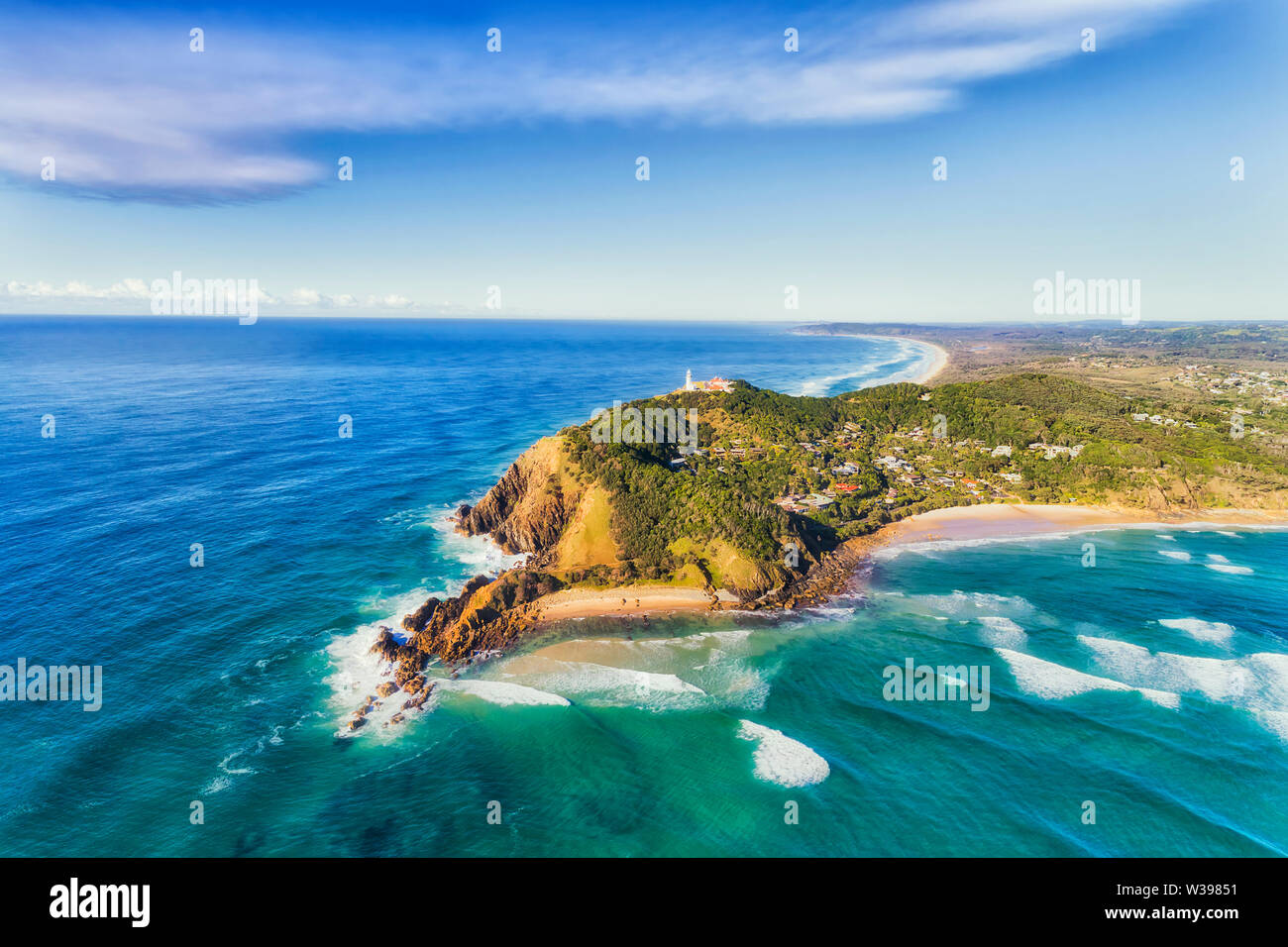 Byron Bay lighthouse high on the rocky headland - the most eastern point of Australian continent facing Pacific ocean in elevated aerial seascape abov Stock Photo