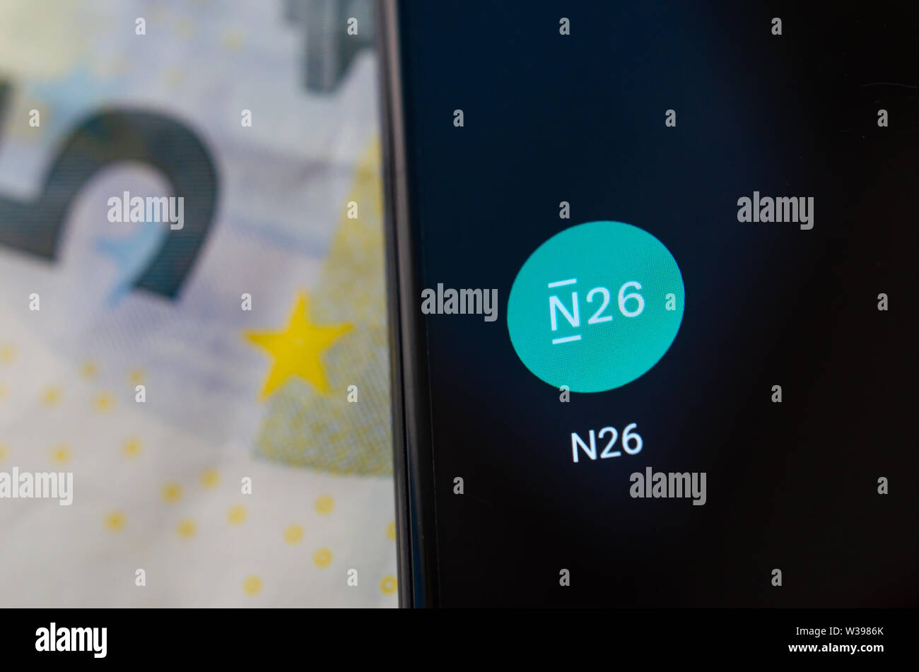 N26 Mobile Bank app on the smartphone screen in a main focus and the euro banknote at the blurred background. Stock Photo
