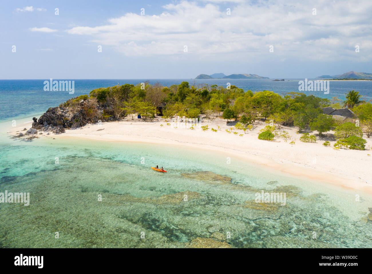 Couple kayaking on a tropical beach with blue water and palm trees ...