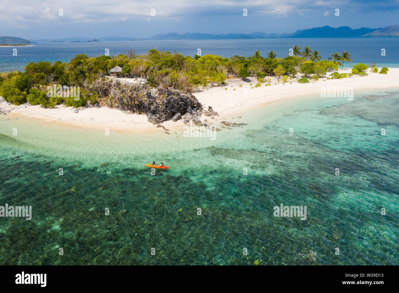 Couple kayaking on a tropical beach with blue water and palm trees ...
