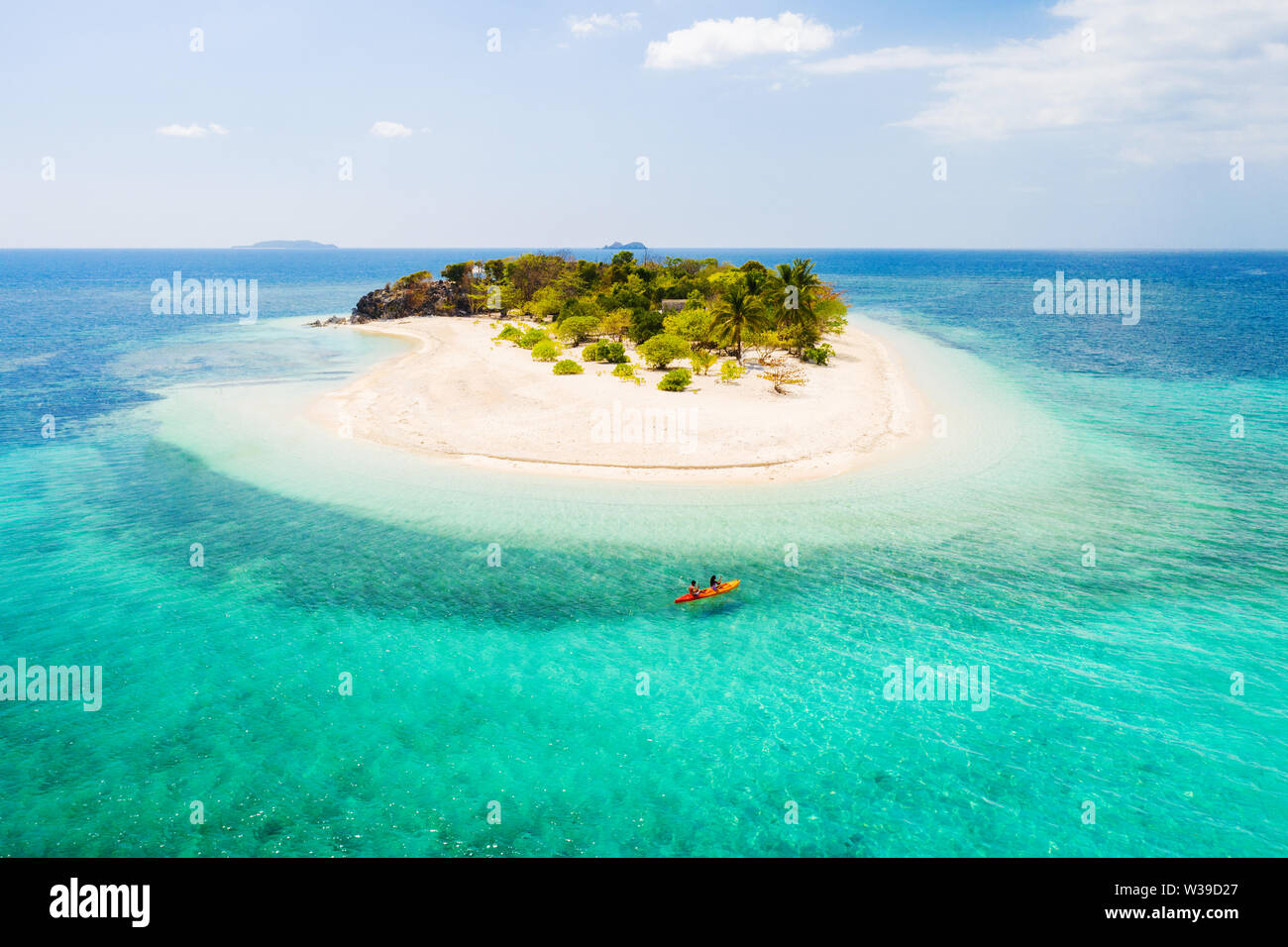 Couple kayaking on a tropical beach with blue water and palm trees ...