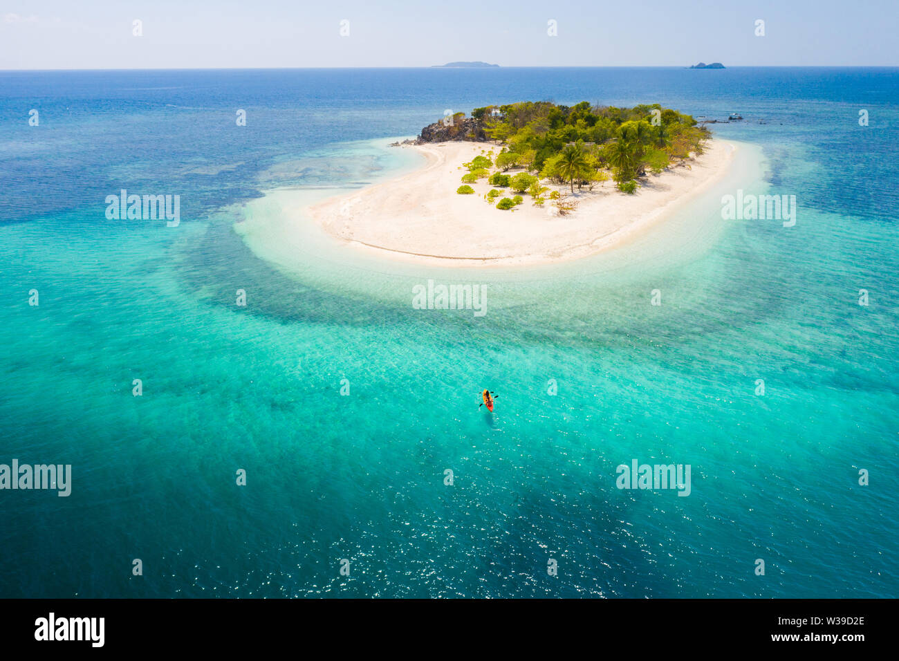 Couple kayaking on a tropical beach with blue water and palm trees ...
