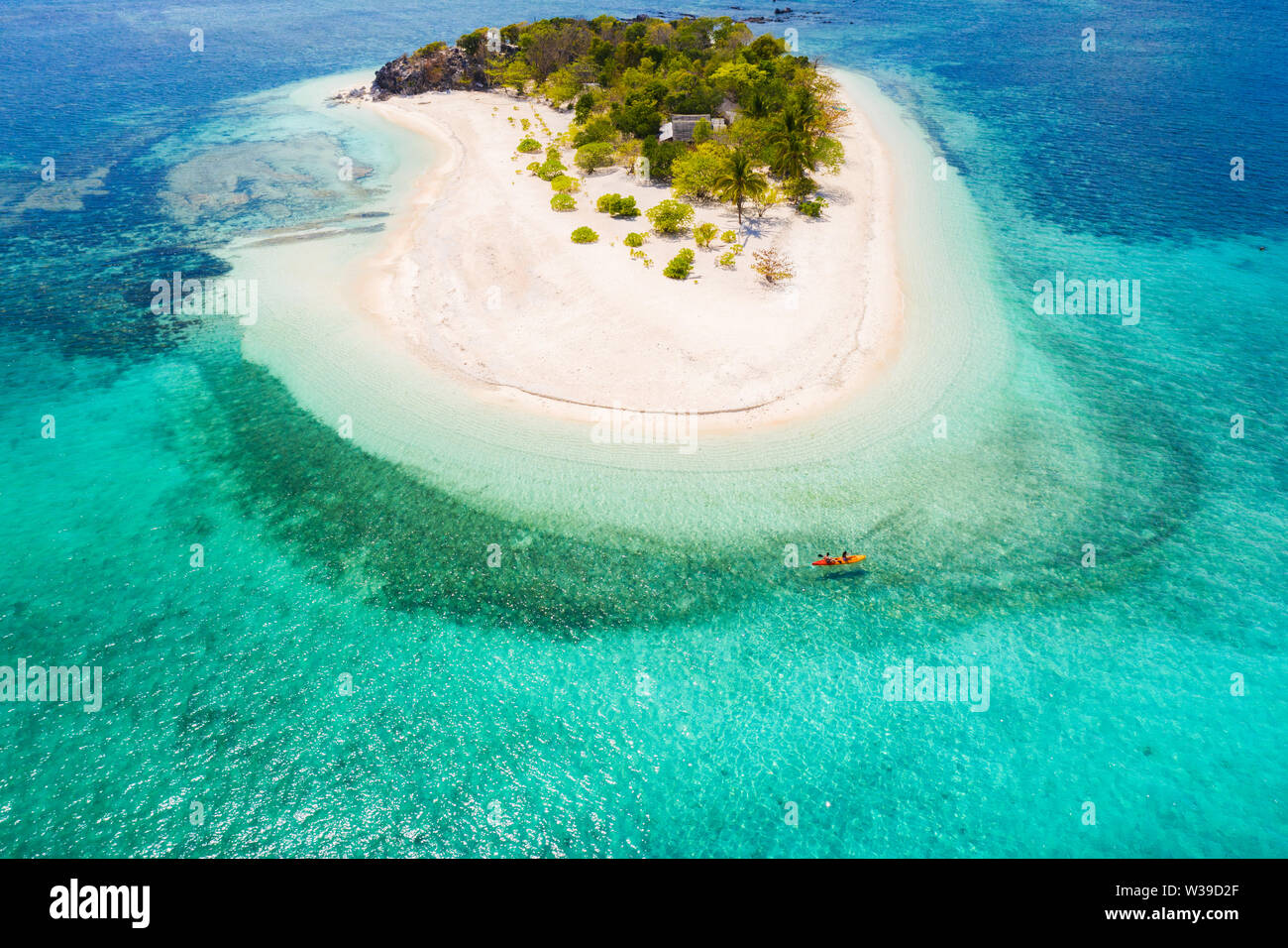 Couple kayaking on a tropical beach with blue water and palm trees ...