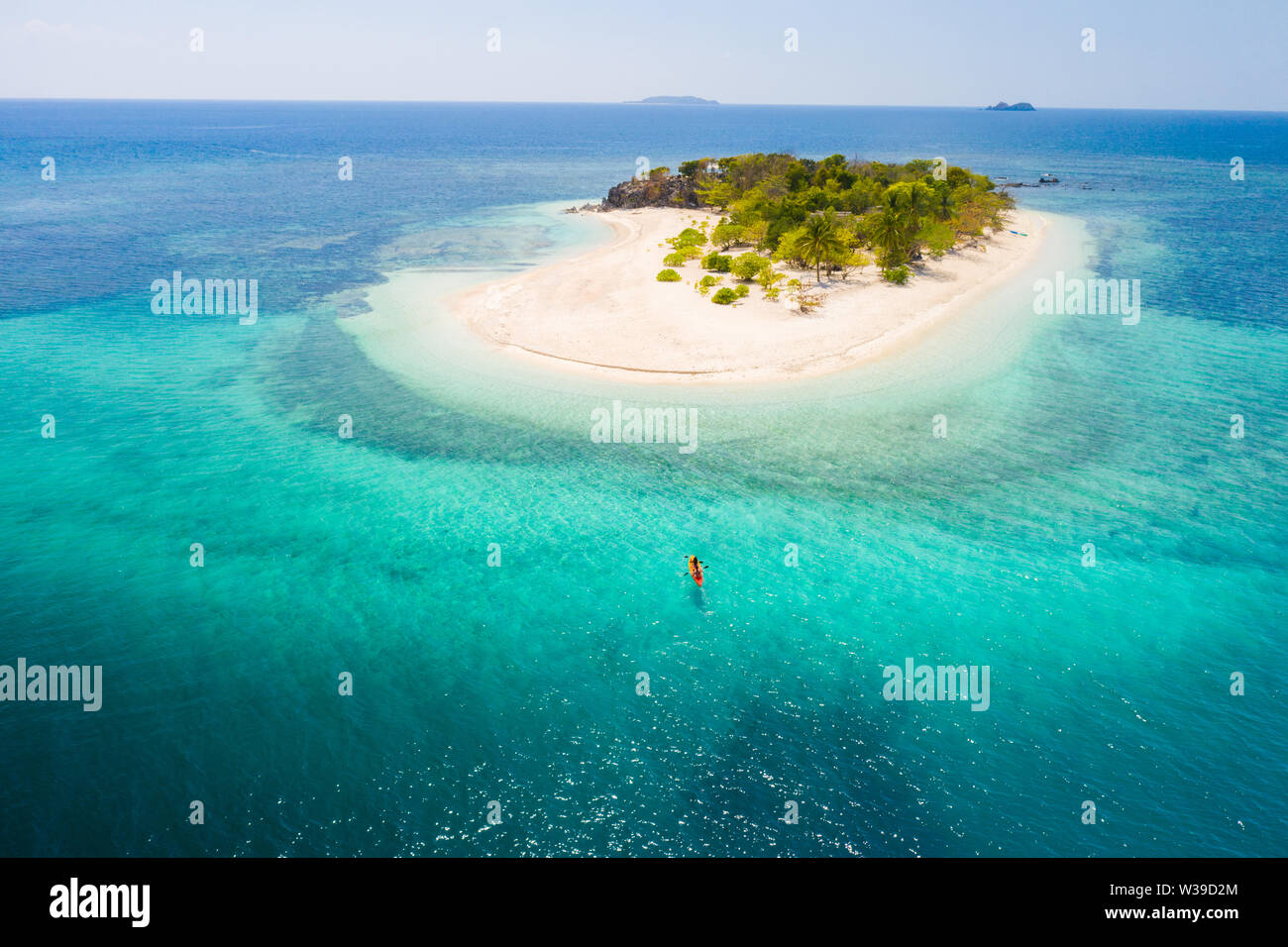 Couple kayaking on a tropical beach with blue water and palm trees ...