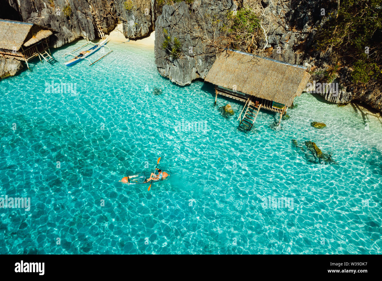 Tourist paddling on a transparent kajak on a tropical beach with blue water  and palm trees - Coron, Philippines Stock Photo - Alamy