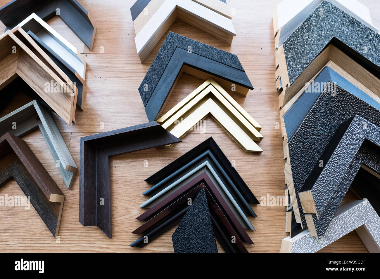 Various picture frame corner samples in different colors and materials arranged on a wooden surface for selection Stock Photo