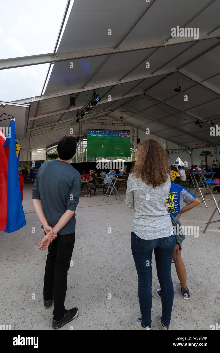 People stop along the Städtle in Vaduz, Liechtenstein to watch a 2018 FIFA World Cup game on the big screen television. Stock Photo