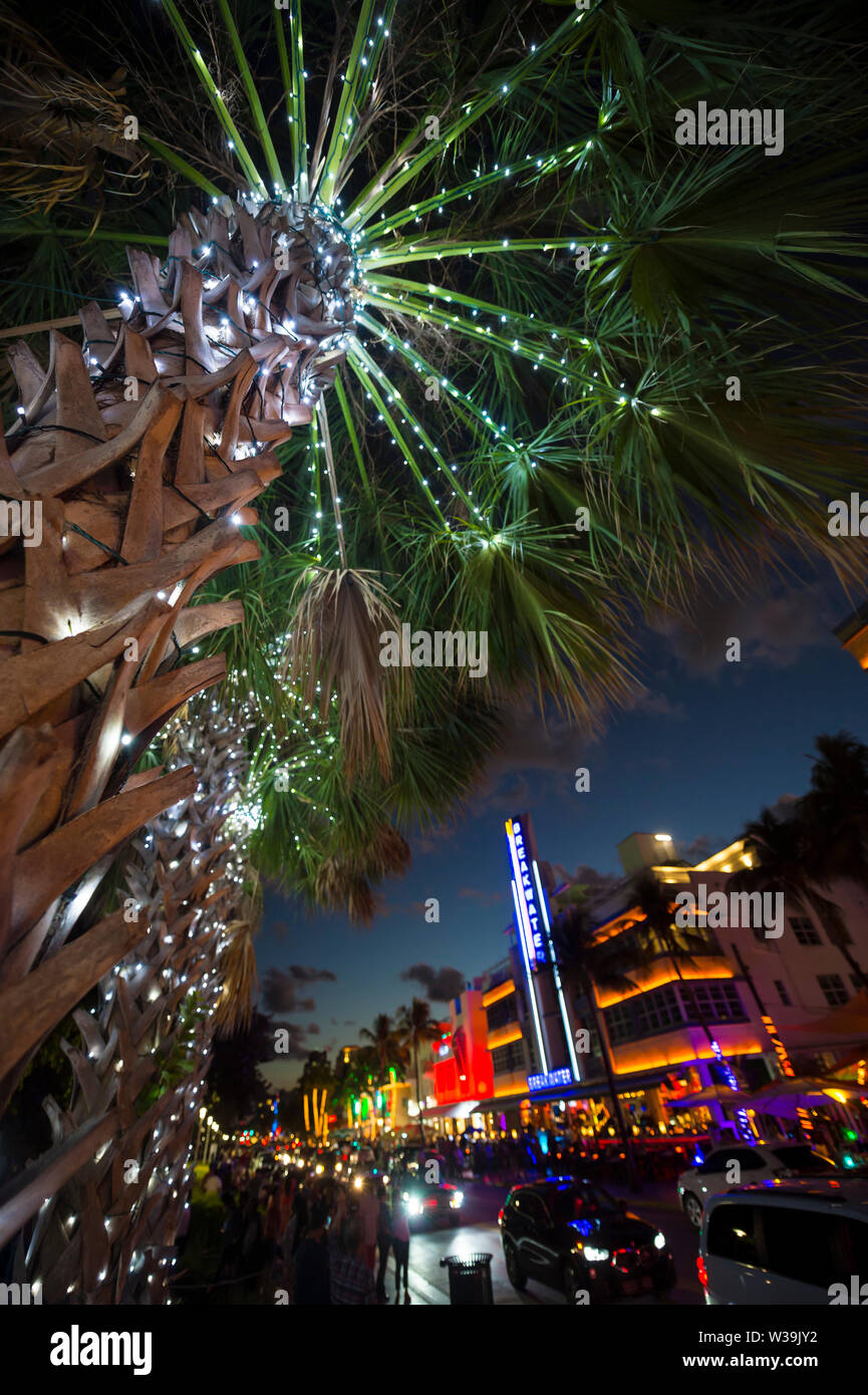 MIAMI - DECEMBER 30, 2018: Visitors stroll along the lights of Ocean Drive, with Art Deco neon lights and holiday palm trees. Stock Photo