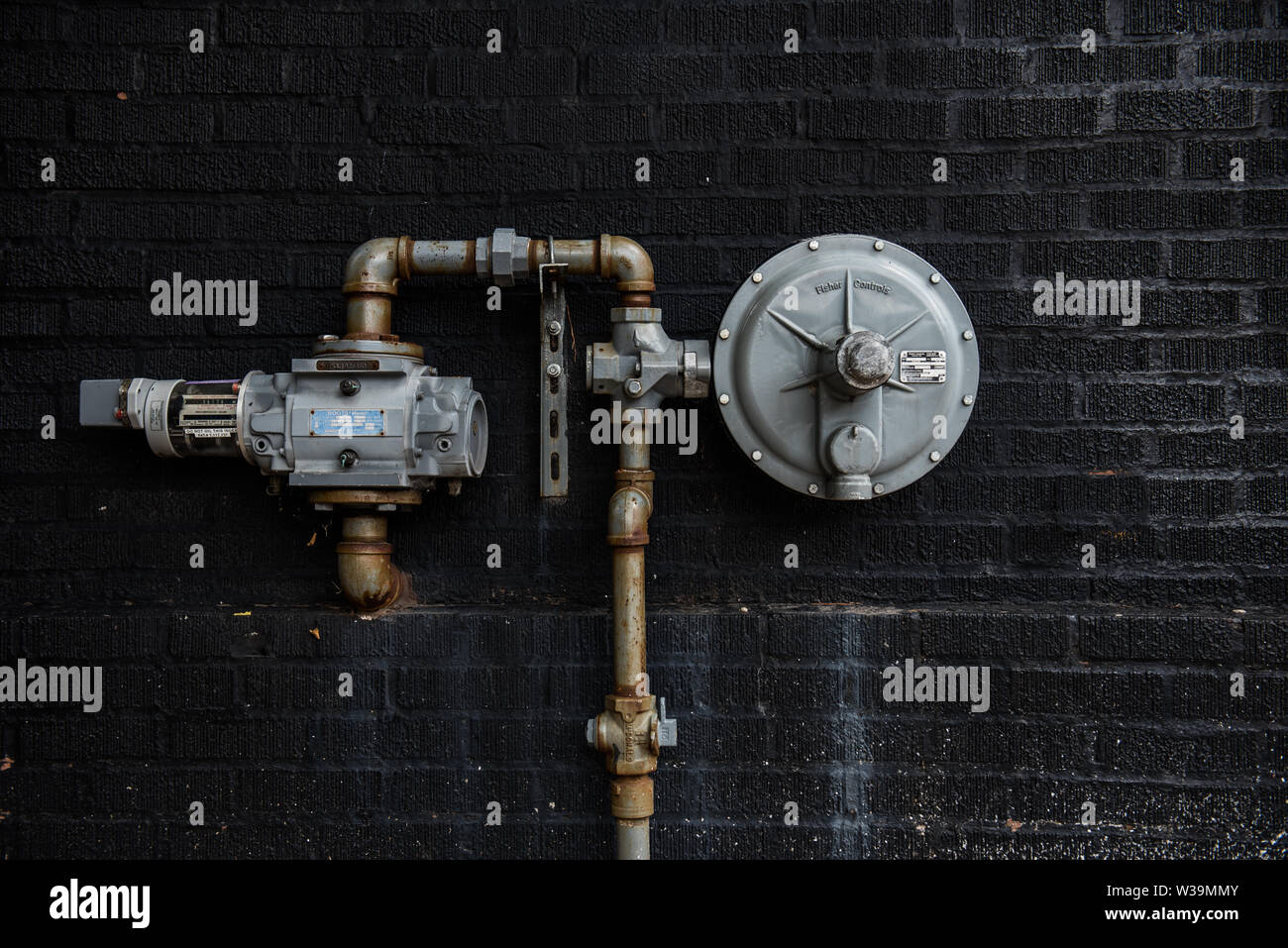 Gas meter mounted on black brick wall on west Belmont avenue, Chicago Illinois, Stock Photo