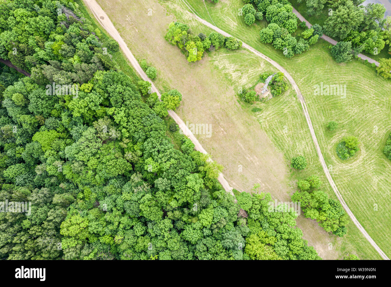 green landscape with country road in the field near deciduous forest. natural rural landscape, aerial top view Stock Photo
