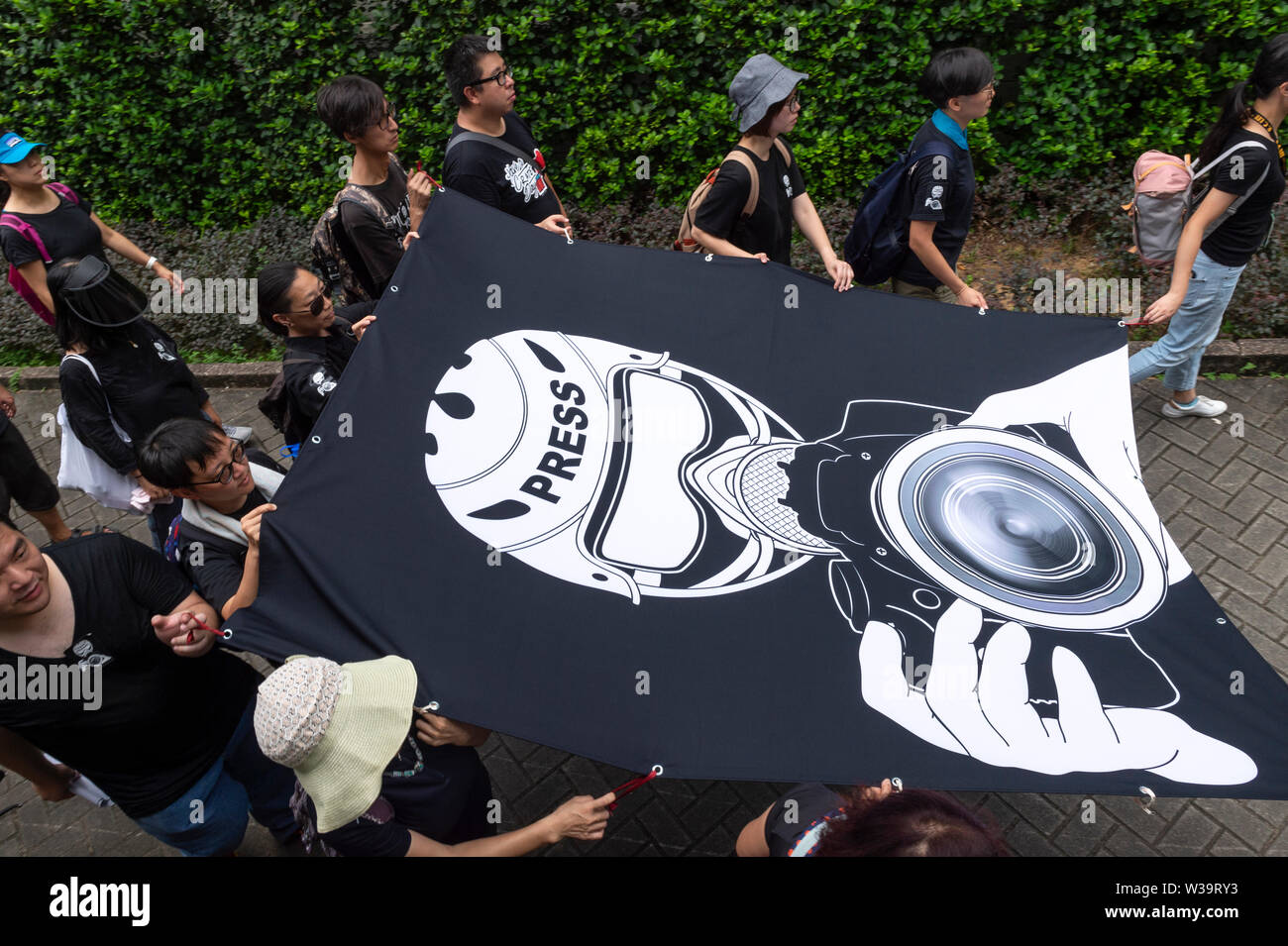 Hong Kong, China. 14th July, 2019. Silent march in Hong Kong to stop police violence and defend press freedom sees working press, journalism students and their educators both past and present gather to protest. Protesters walk the perimeter of he Police Headquarters.The crowd wore all black in a show of solidarity. Credit: Jayne Russell/Alamy Live News Stock Photo