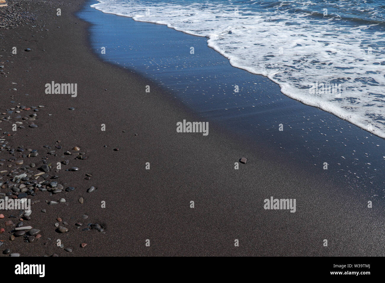 Black Fine Volcanic Sand Beach And Pebbles On Bali Island In Indonesia The Sea Water Reaches The Coast And Turns Into Sea Foam Wet Black Sand Stock Photo Alamy