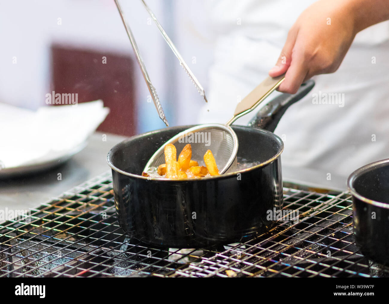 Chef is cooking french fries in the kitchen, Chef cooking fried potato in pan Stock Photo