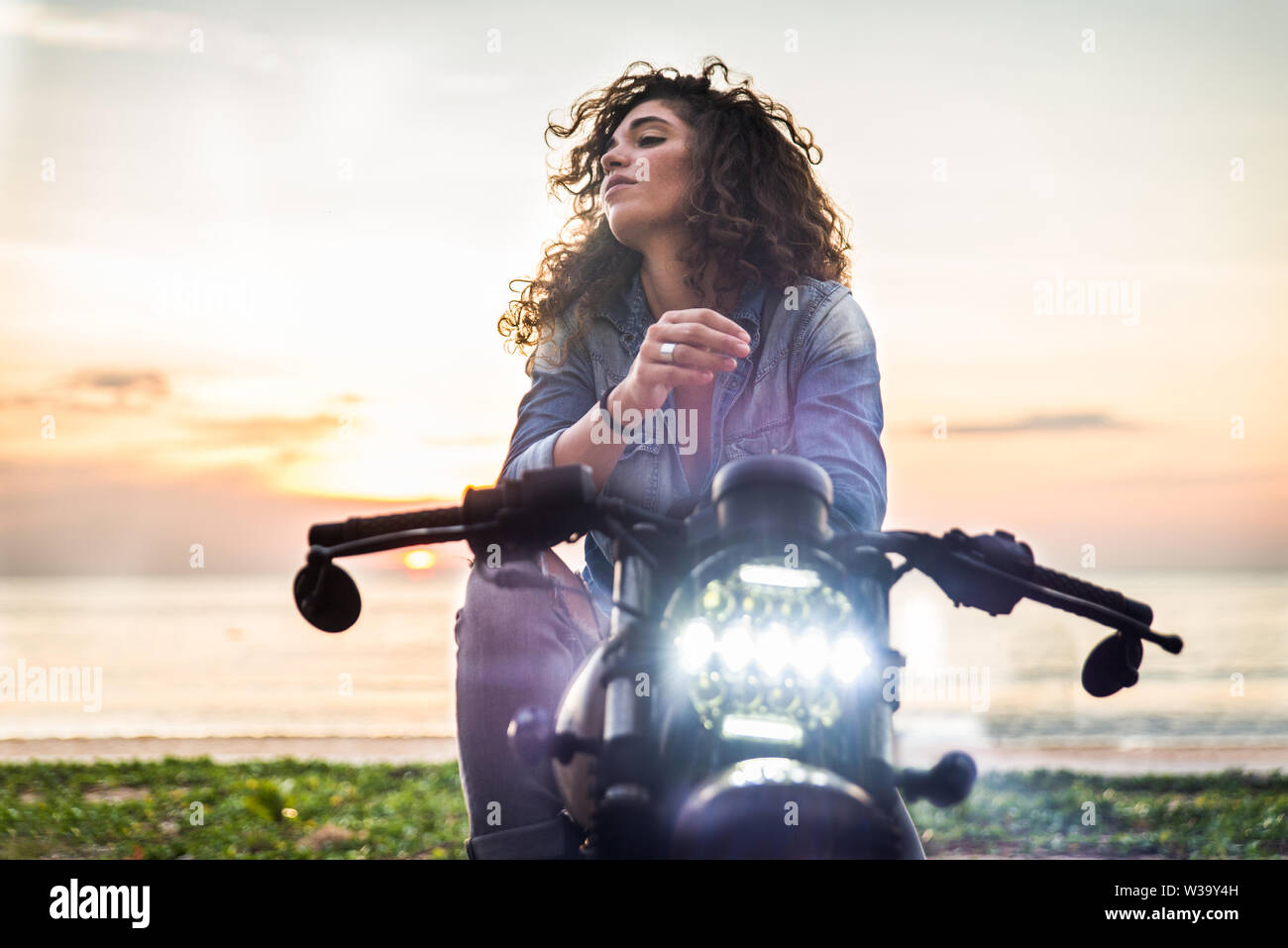 Beautiful female biker driving a cafe' racer motorbike Pretty girl