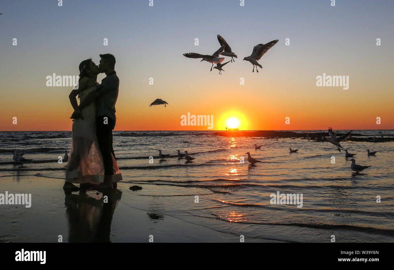 A couple kisses at sunset while seagulls hovered at Brighton Beach Melbourne. Stock Photo