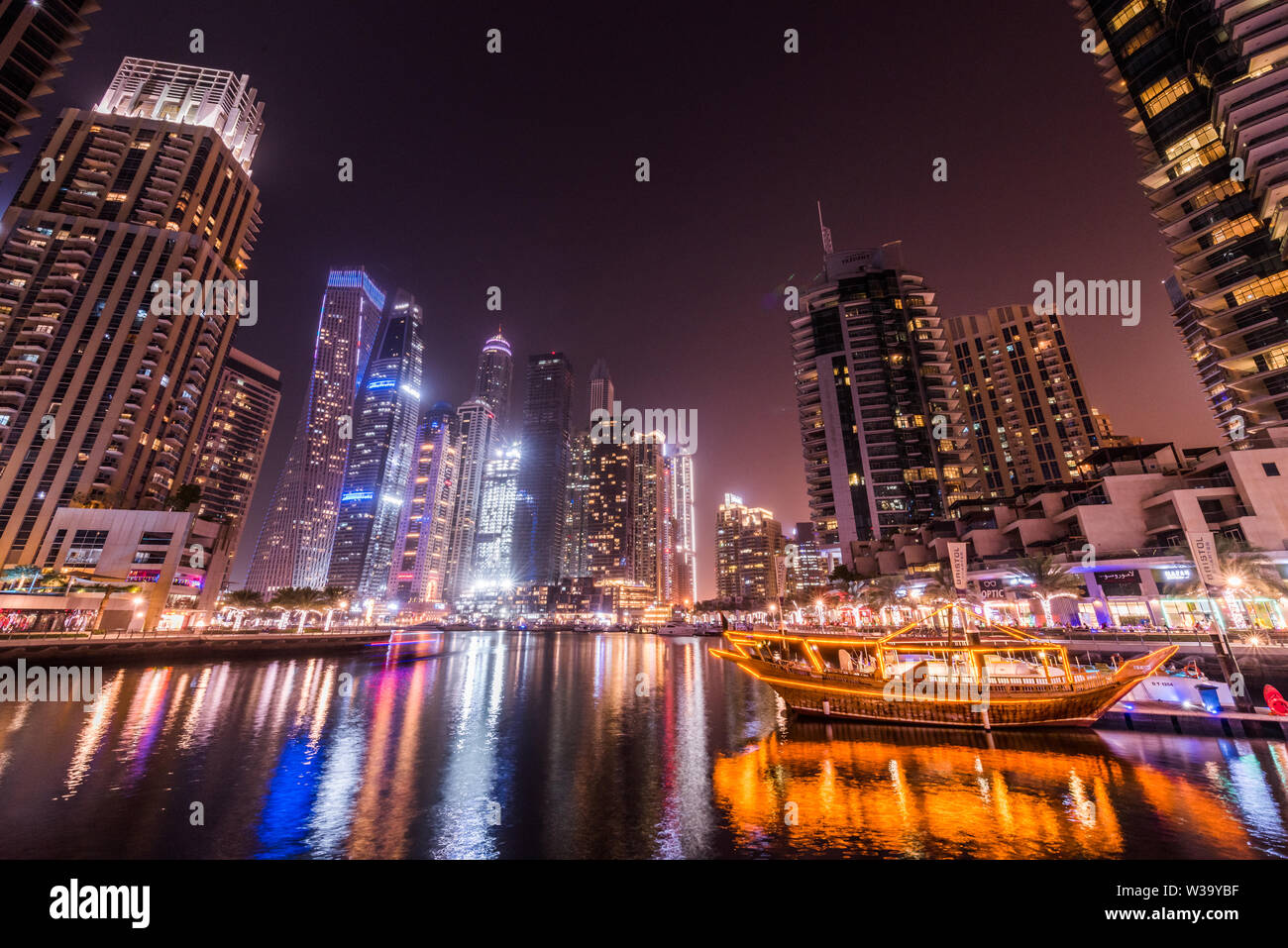 Buildings, lights, water, boat, skyscrapers, palm trees, feelings, emotions. Spectacular images. Dream landscapes. A fascinating city. Night in town. Stock Photo