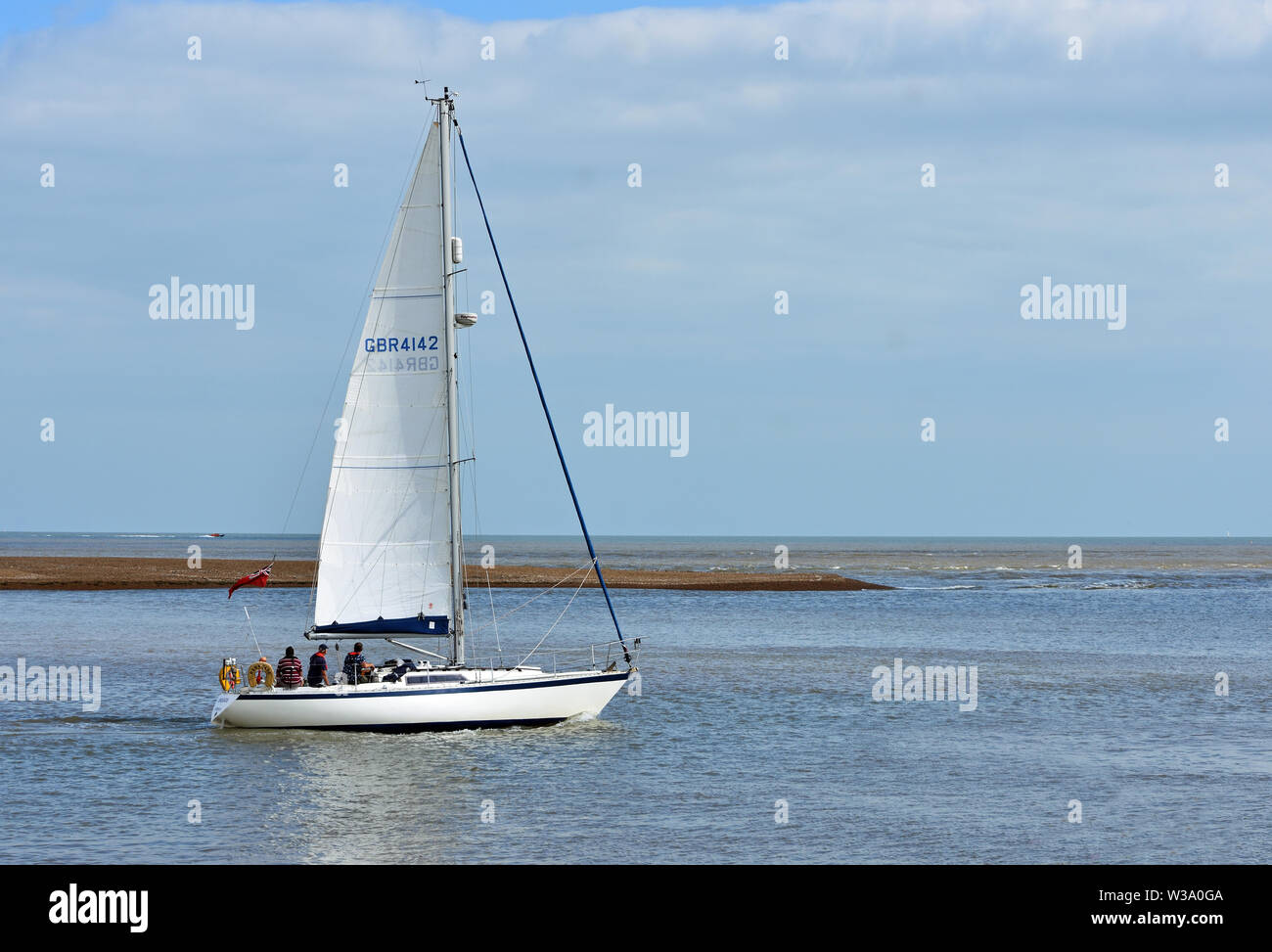 Yacht leaving Felixstowe Ferry at the mouth of the river Deben. Stock Photo