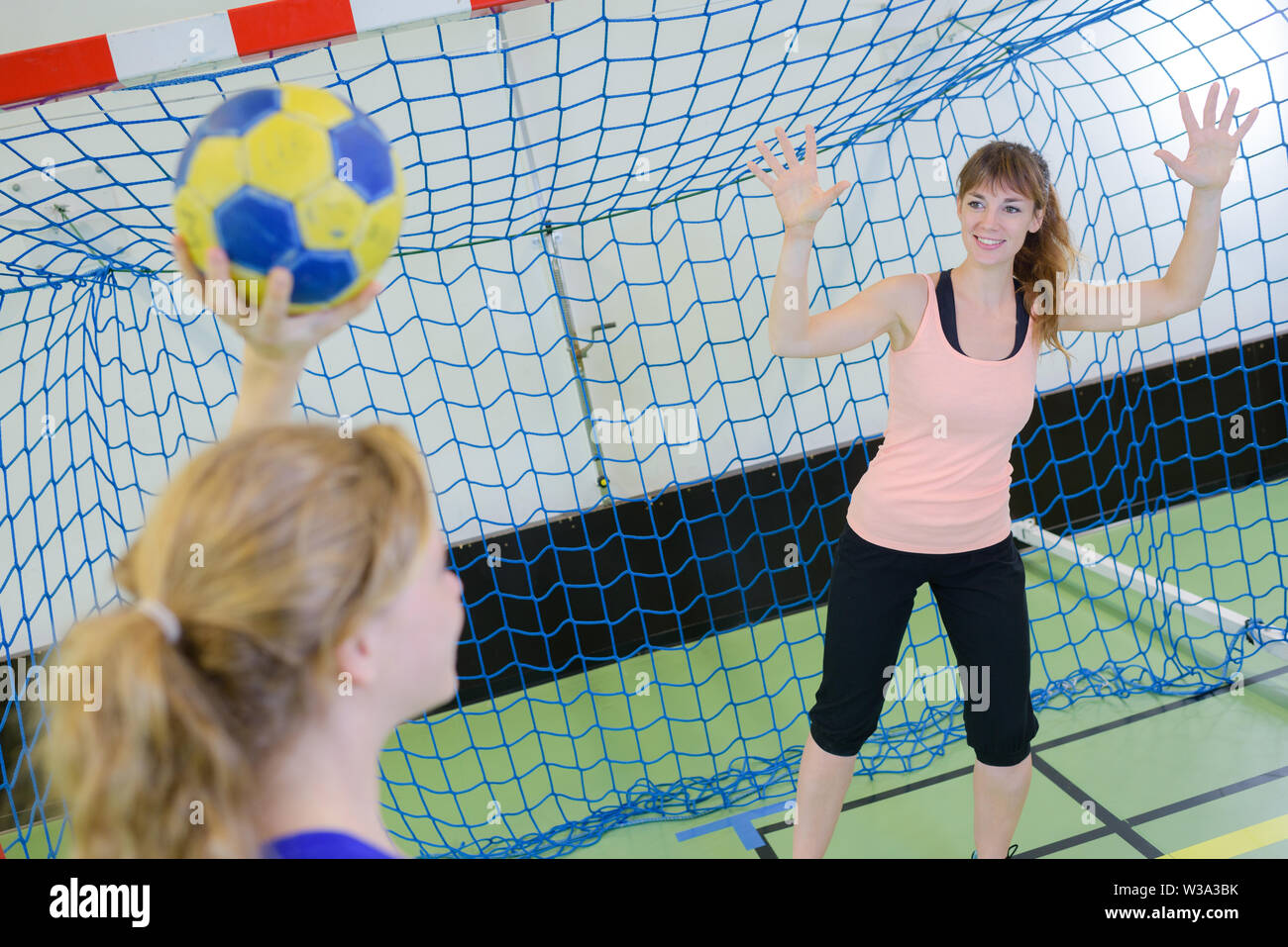 sportswoman holding a ball against handball field indoor Stock Photo