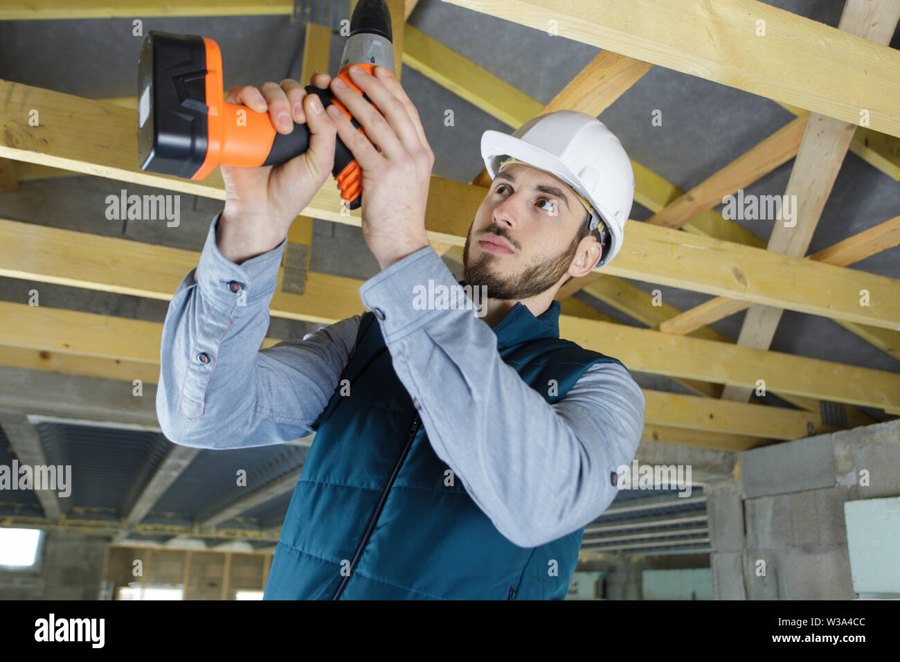 worker drilling wood beam during remodeling Stock Photo Alamy