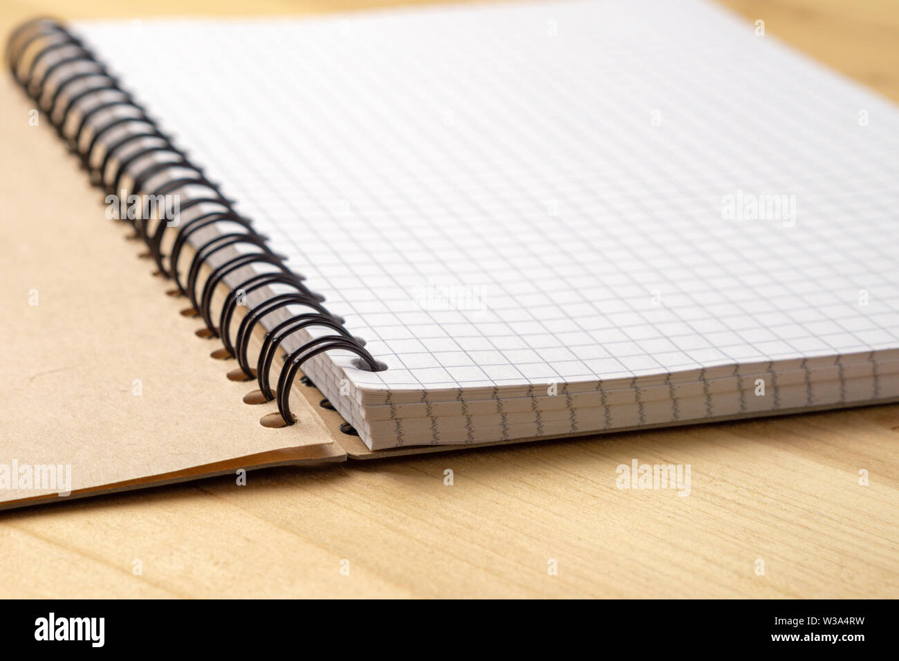 Notebook with checkered sheets on a wooden table. Side view Stock Photo