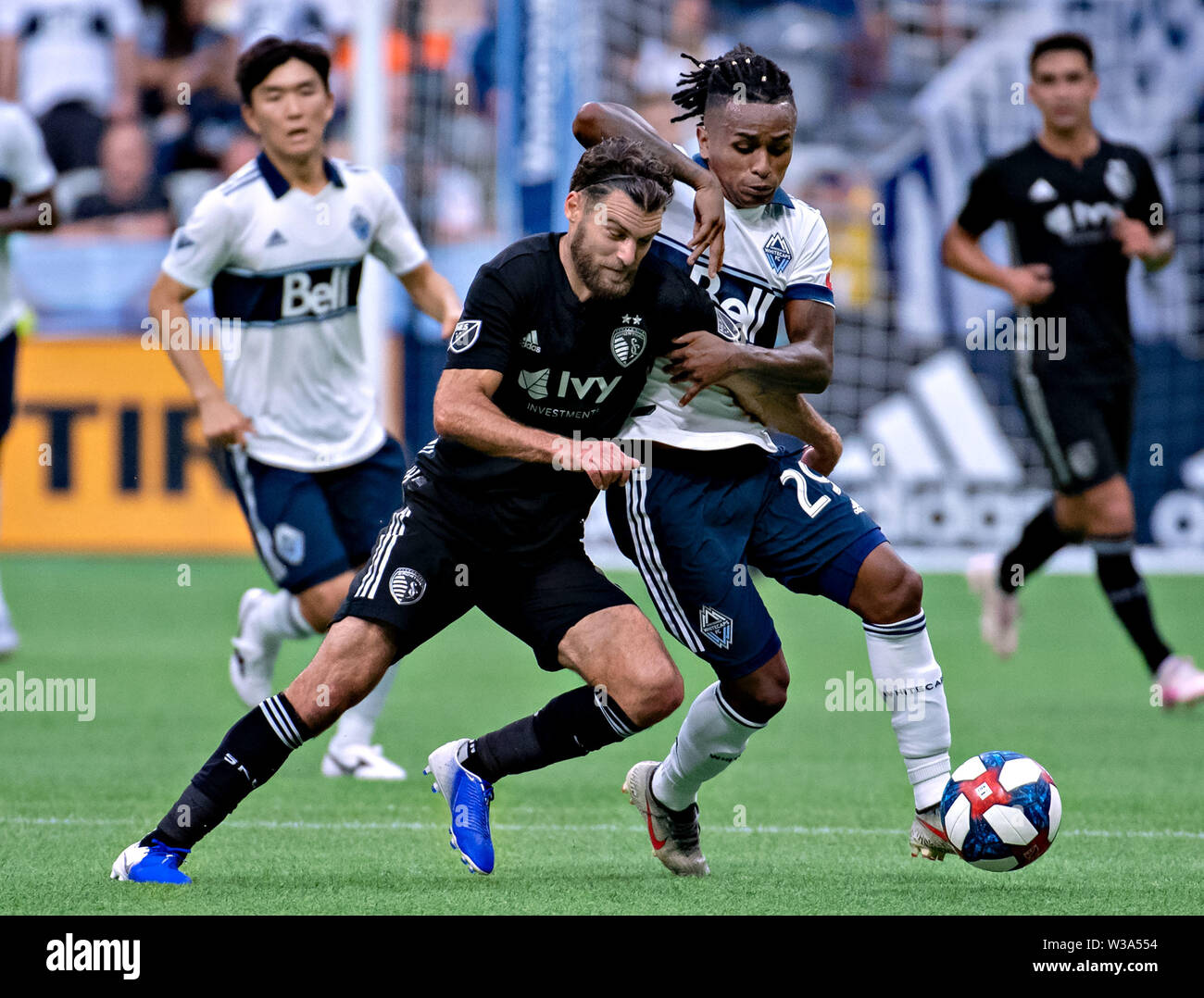 Vancouver, Canada. 14th July, 2019. Sporting Kansas City's Graham Zusi (L) vies with Vancouver Whitecaps FC's Yordy Reyna during the MLS regular season soccer match between Vancouver Whitecaps FC and Sporting Kansas City in Vancouver, Canada, July, 13, 2019. Sporting Kansas City won 3-0. Credit: Andrew Soong/Xinhua/Alamy Live News Stock Photo