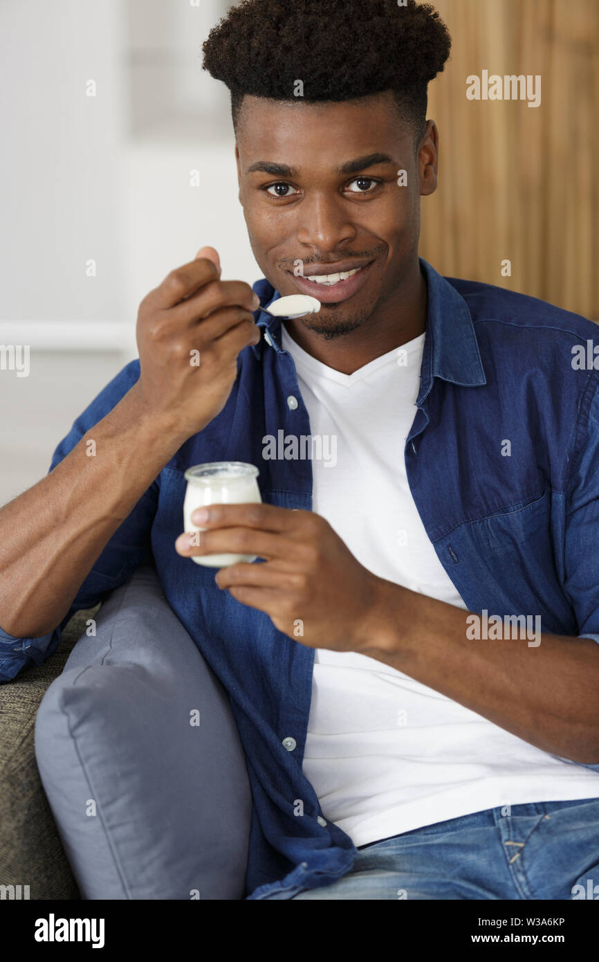 a young man eating yogurt Stock Photo Alamy