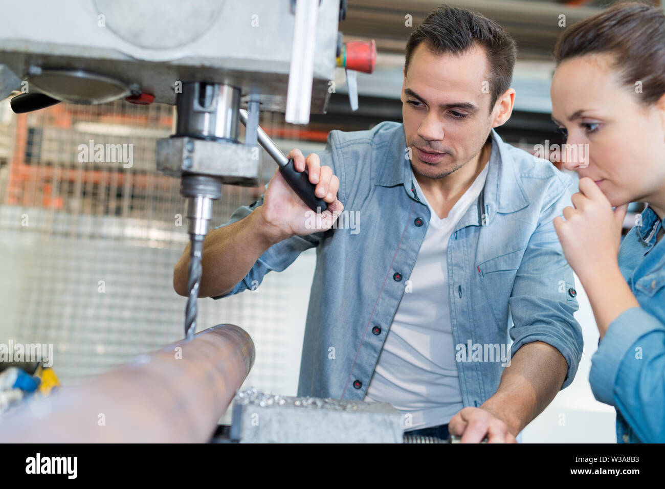young technicians working on pillar drilling machine in workshop Stock Photo