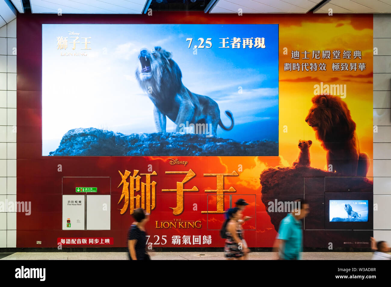 Hong Kong, Hong Kong - Jul 10, 2019: Lion King big movie poster and large TV screen showing movie trailer in public subway walkway. Cinema promotional Stock Photo