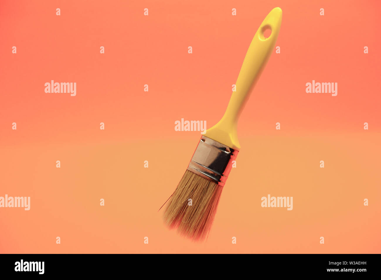 New yellow paint brush on a living coral background Stock Photo Alamy