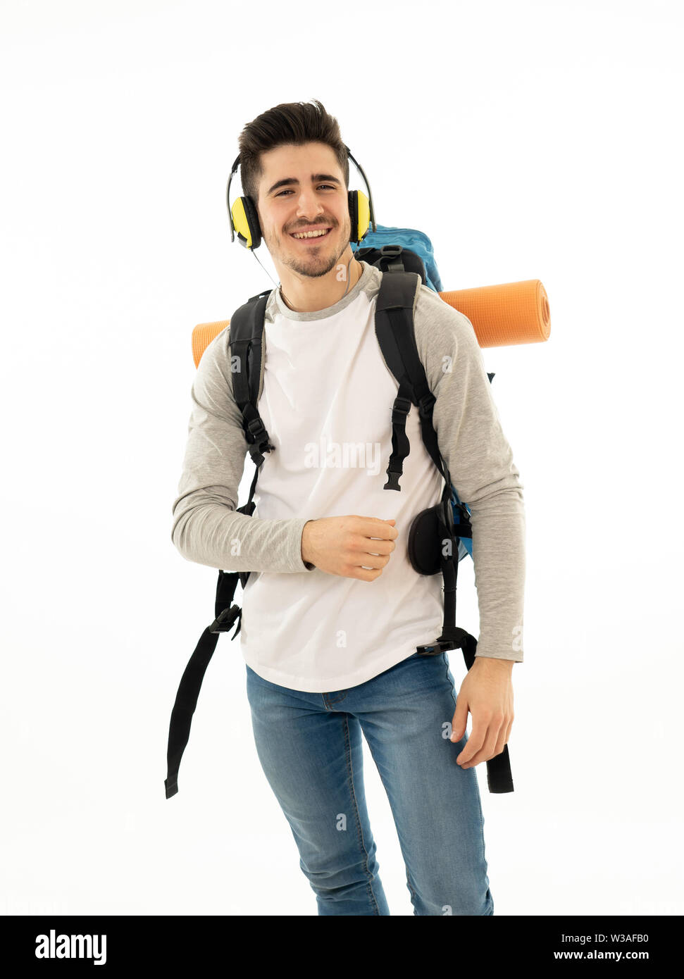 Portrait of happy young student man with backpack listening to music in ...