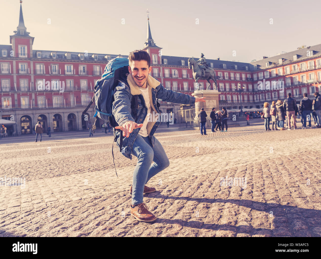 Happy young man traveling around Europe having fun pretending to surf in Plaza de Espa–a, Madrid, Spain. In People Vacations, adventure, backpacking, Stock Photo