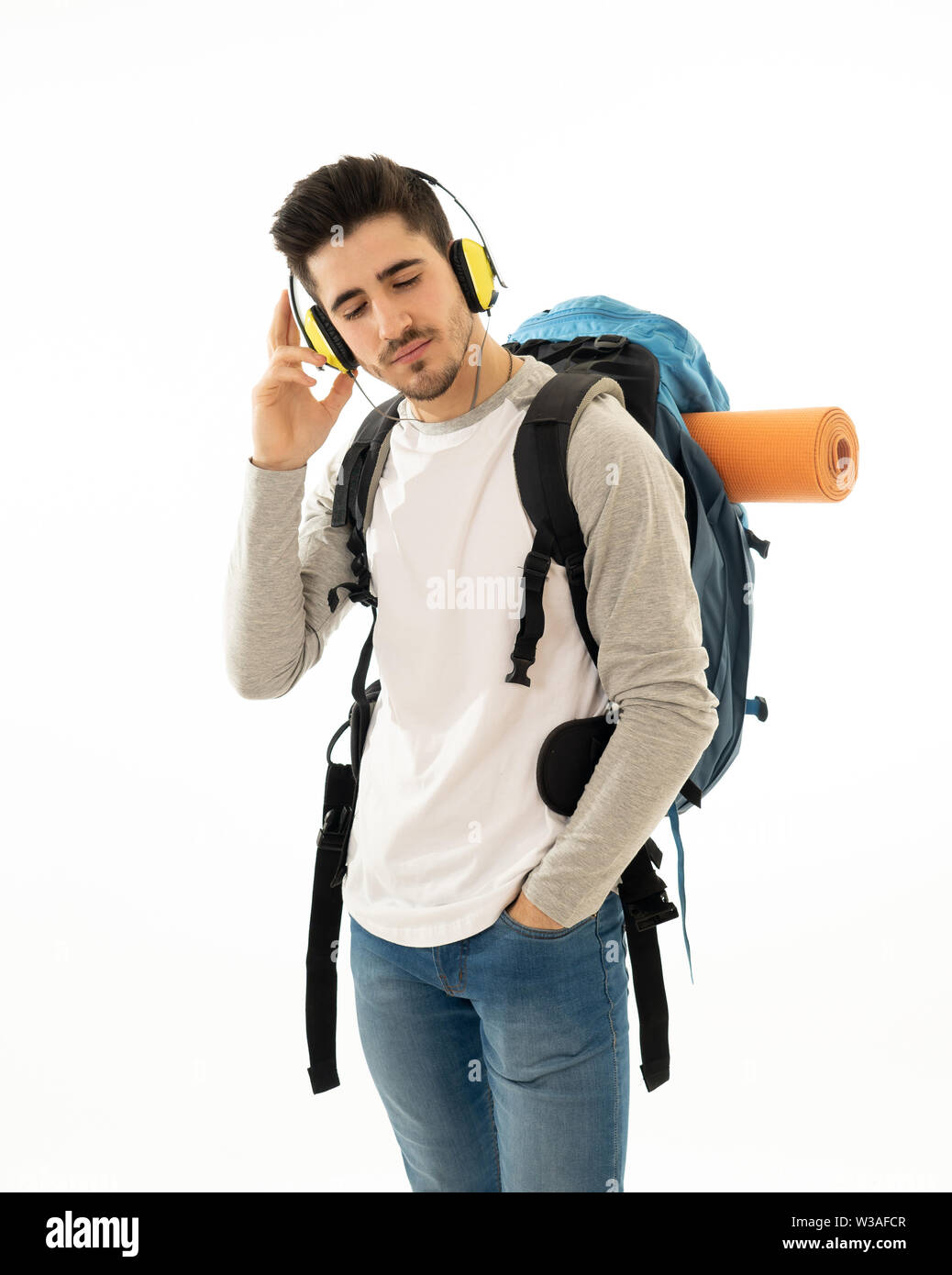 Portrait of happy young student man with backpack listening to music in ...