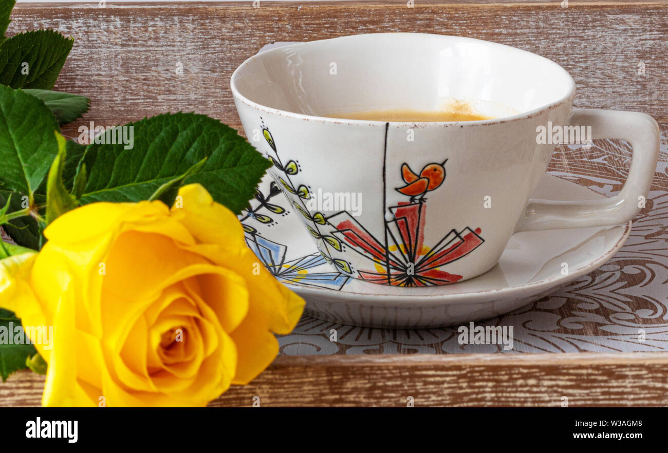 Beautiful yellow rose with cup of coffee on a wooden table ...