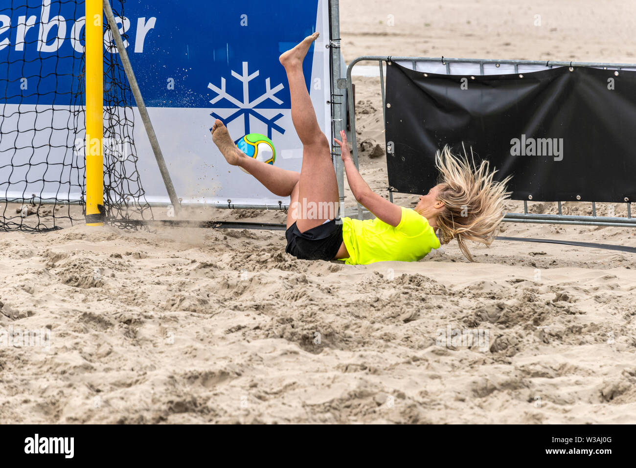 female beach soccer goalkeeper falling on the sand Stock Photo