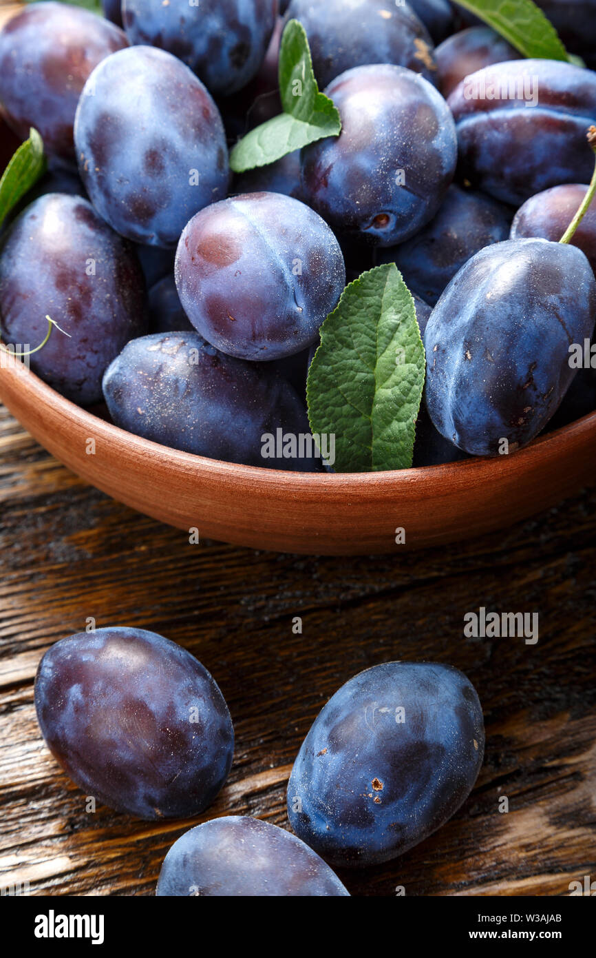 fresh crop of ripe organic plums in a plate on the table as background ...