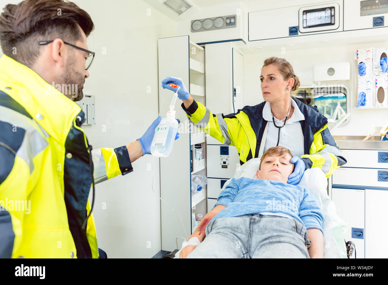 Emergency doctor and paramedic giving infusion in ambulance Stock Photo