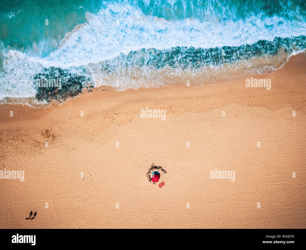 Aerial view of ocean waves and sand beach with tourists walking - summer holiday vacation concept with people - blue and yellow colors - tropical scen Stock Photo
