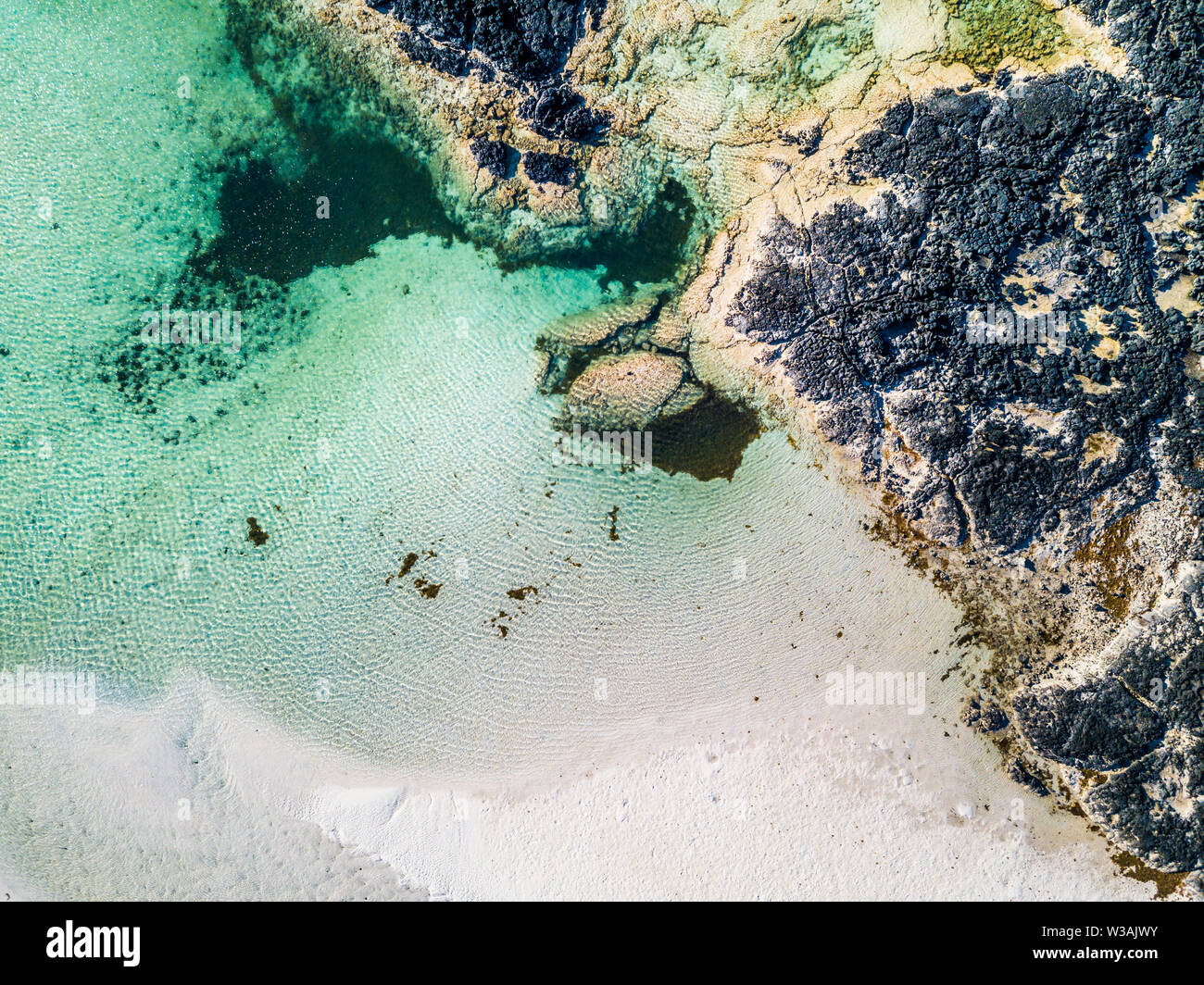 Vertical aerial view of white lagoon sand beach and clear tourquoise water - resort beautiful summer holiday destination with ocean and rocks - paradi Stock Photo