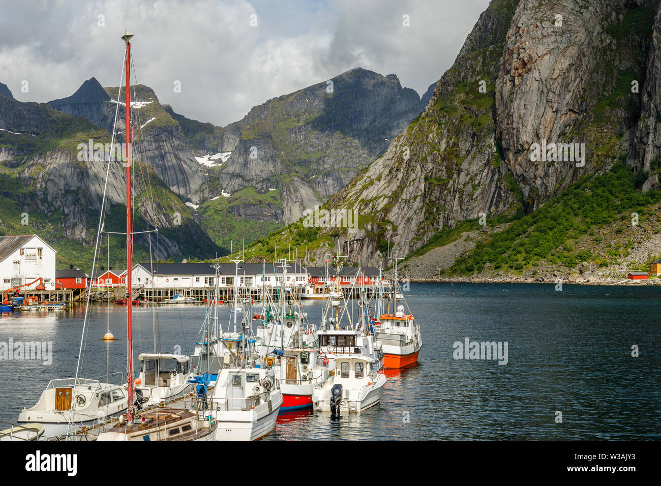Yachts and boats with mountains in the background at pier in Reine, Moskenesoya, Lototen islands,, Nordland County, Norway Stock Photo