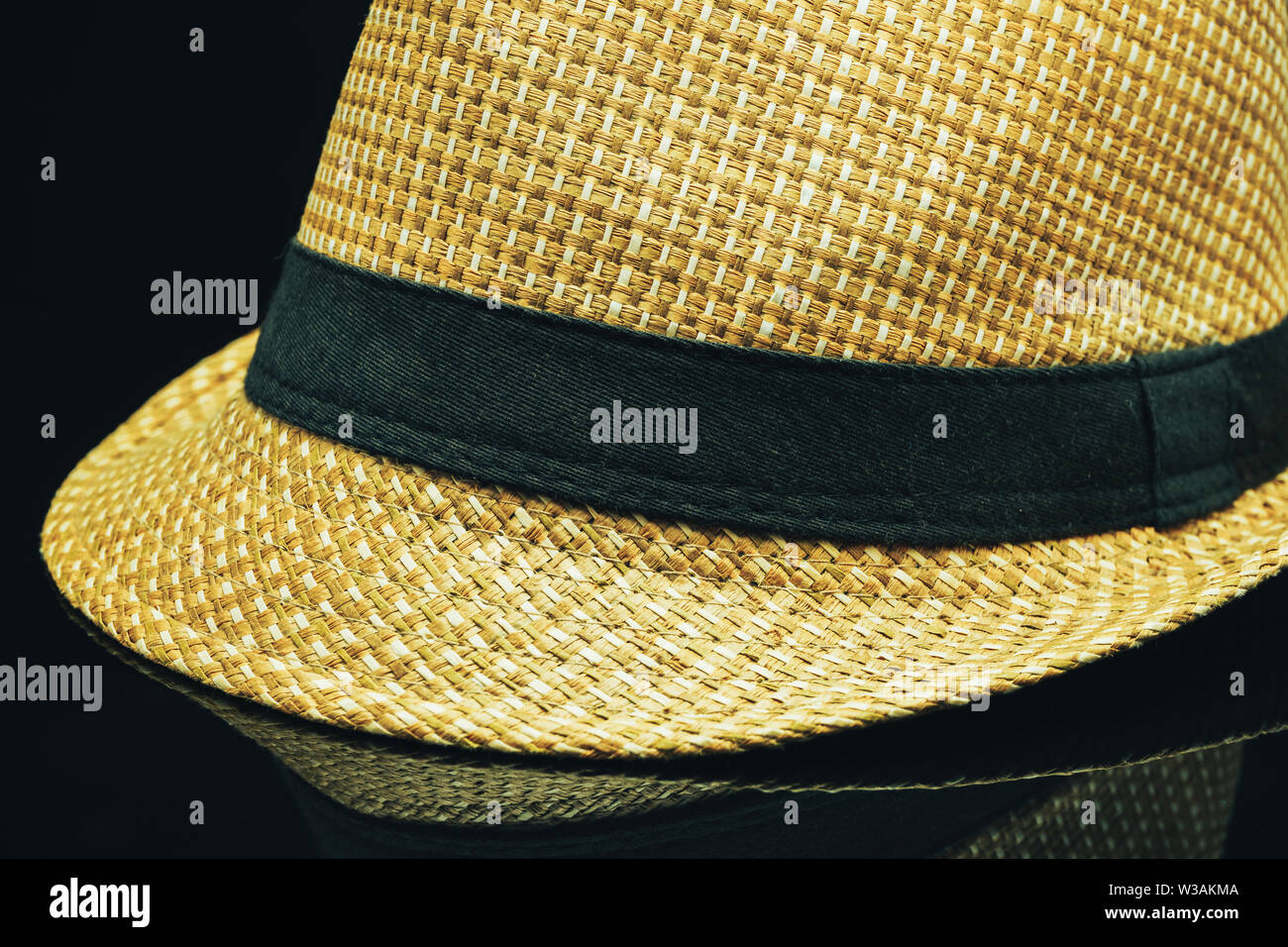 Close up Straw hat on a black glass table background. Stock Photo