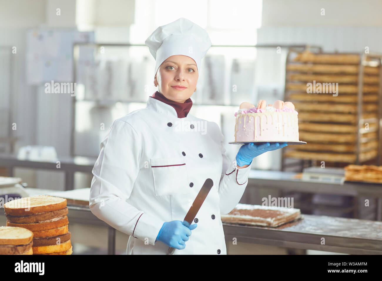 Woman confectioner with pastry cake in his hand smiling at the bakery