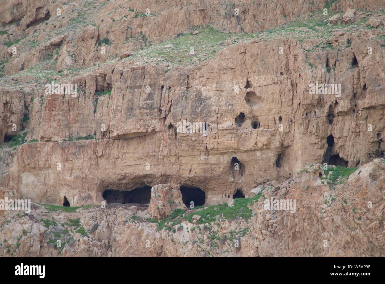 Caves in a red-brown grassed rock Stock Photo