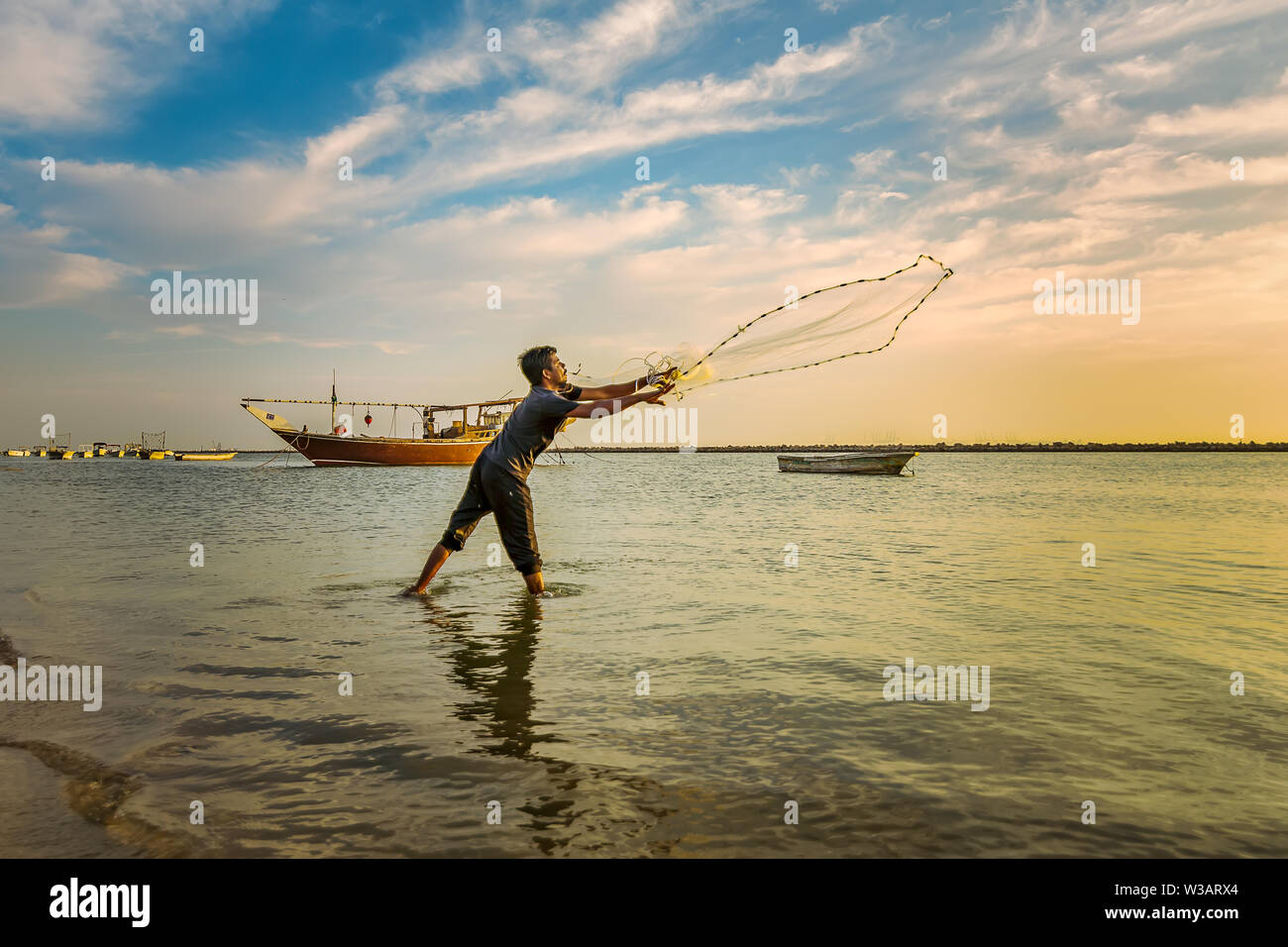Silhouettes of the fishermen throwing fishing net during sunset in