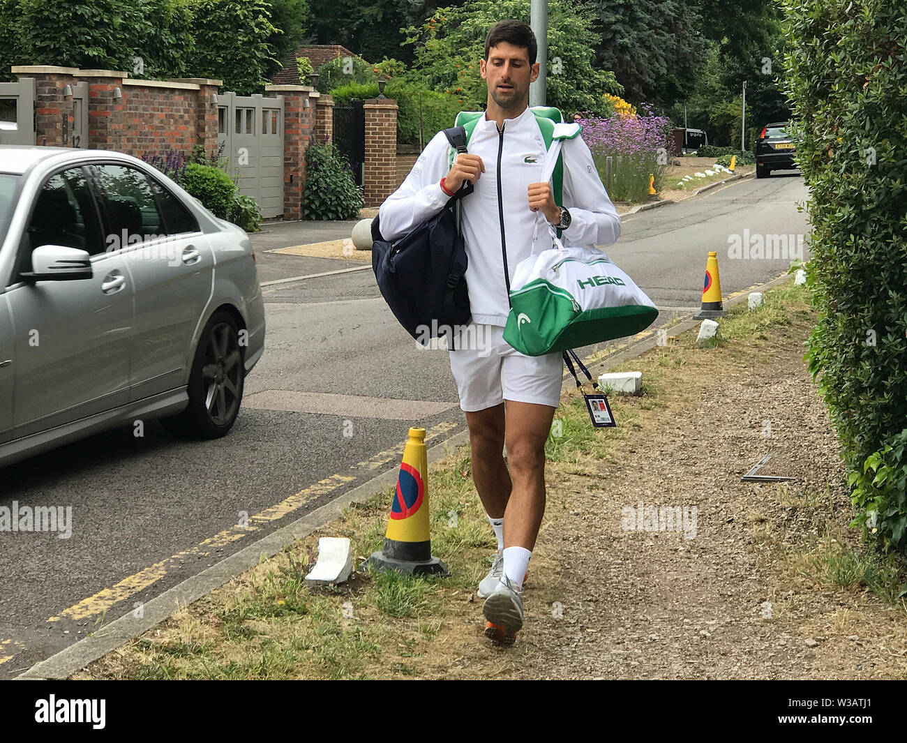 London, UK. 14 July 2019. The Championships Wimbledon 2019 14072019  A penny for your thoughts - Reigning Champion Novak Djokovic strolls from his rented house near Centre Court to face Roger Federer in today’s final. Credit: Roger Parker/Alamy Live News Stock Photo