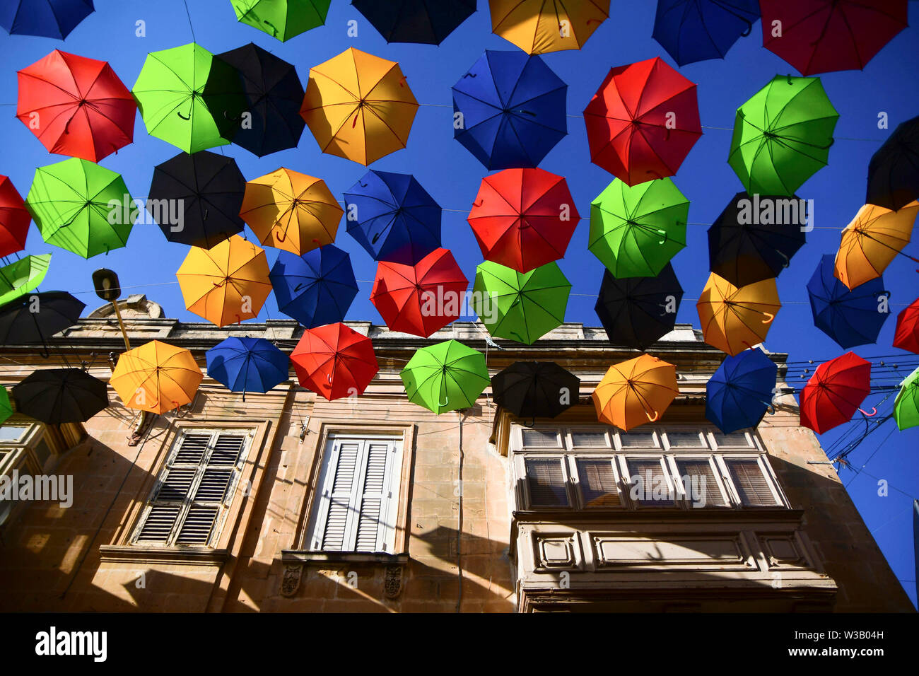Zabbar. 13th July, 2019. Photo taken on July 13, 2019 shows umbrellas suspended in the air along a street to bring back the popular 'Umbrella Street' spectacle in Zabbar, Malta. Credit: Jonathan Borg/Xinhua/Alamy Live News Stock Photo