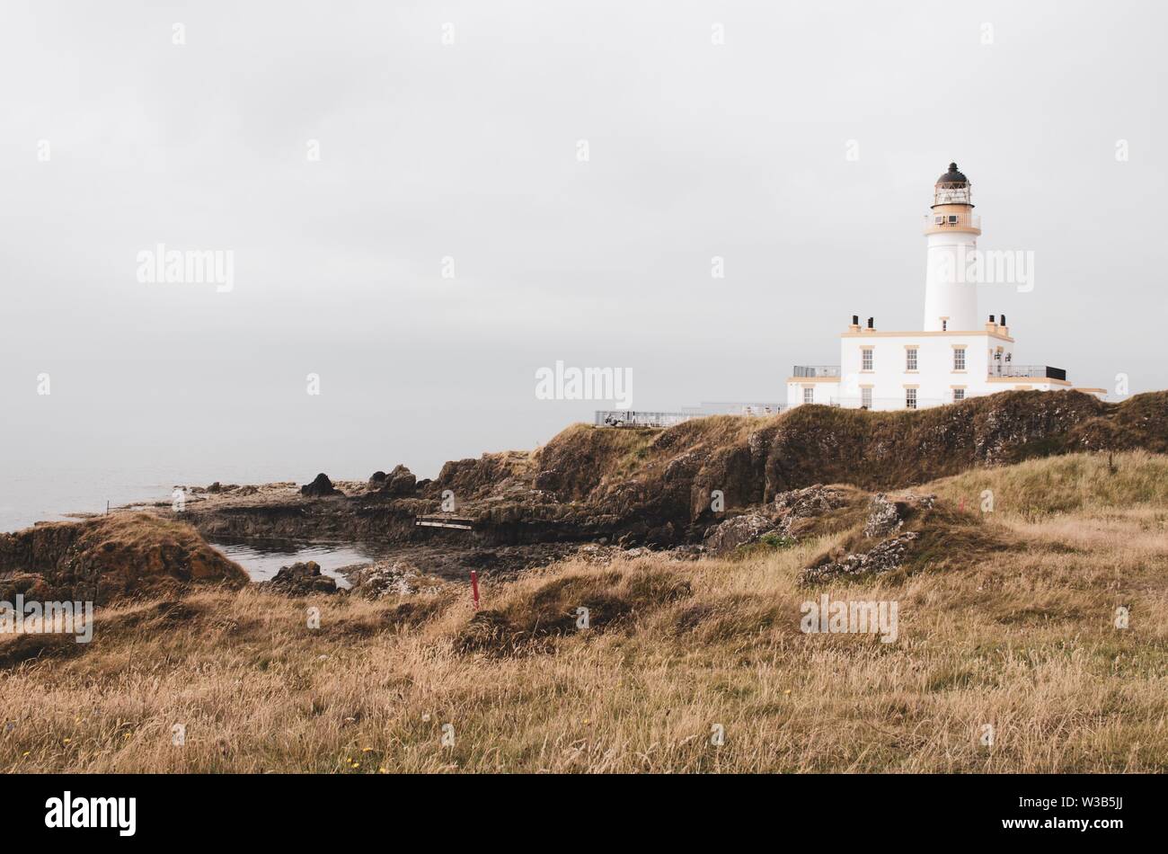 White lighthouse on top of a hill looking out at the Scottish coast. Grassy landscape Stock Photo