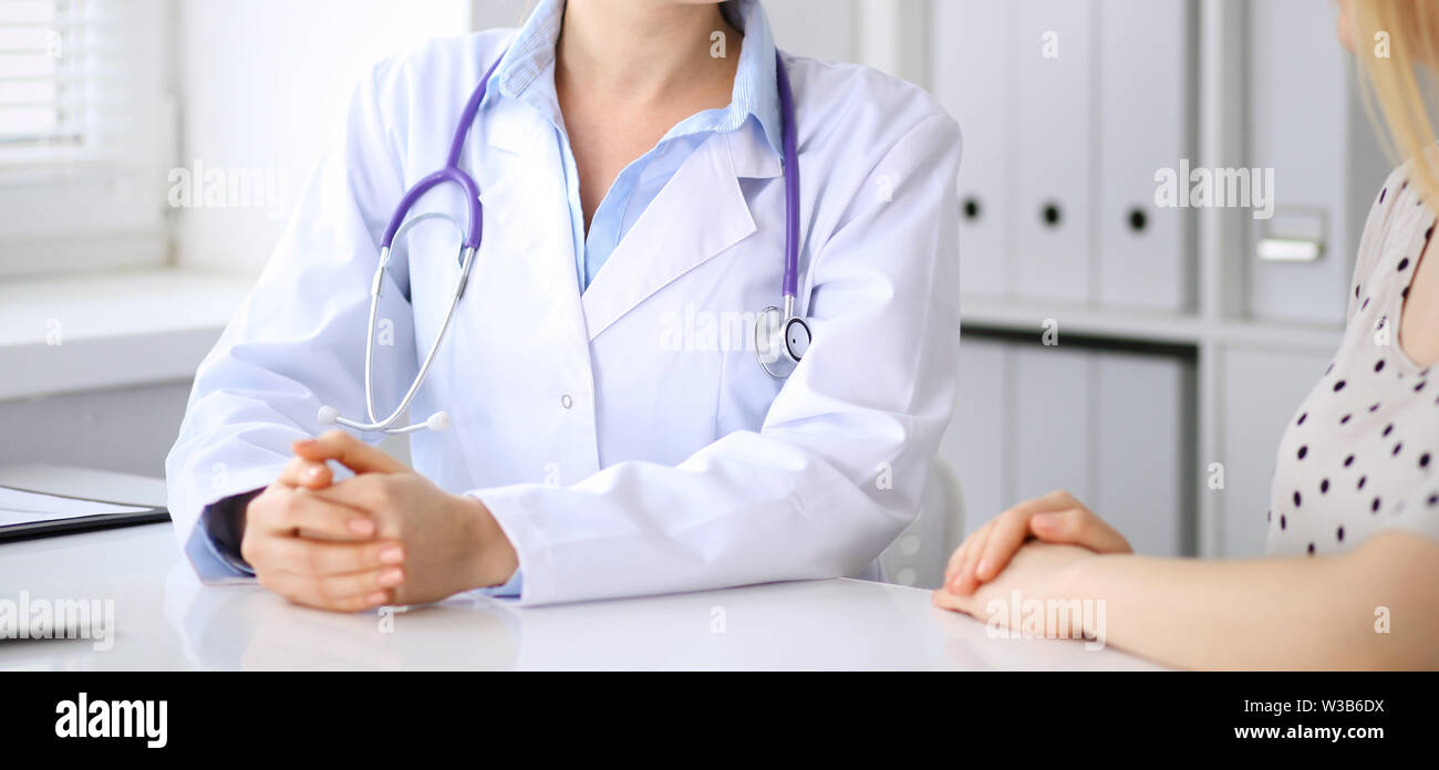 Doctor and patient discussing something while sitting at the desk at ...