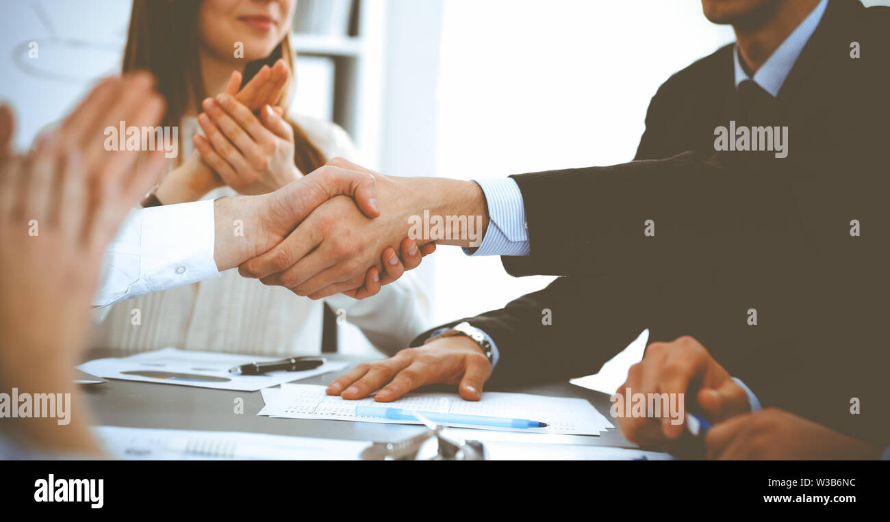 Business people shaking hands at meeting while theirs colleagues ...