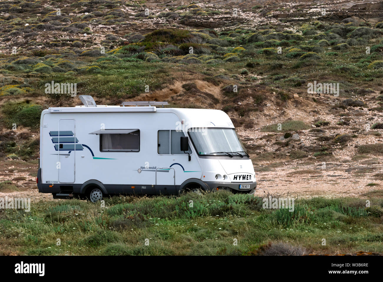Tharros, Sardinia, Italy - June 11, 2019: A white camper motor home is parking on a mountain road, passengers gone hiking. Stock Photo