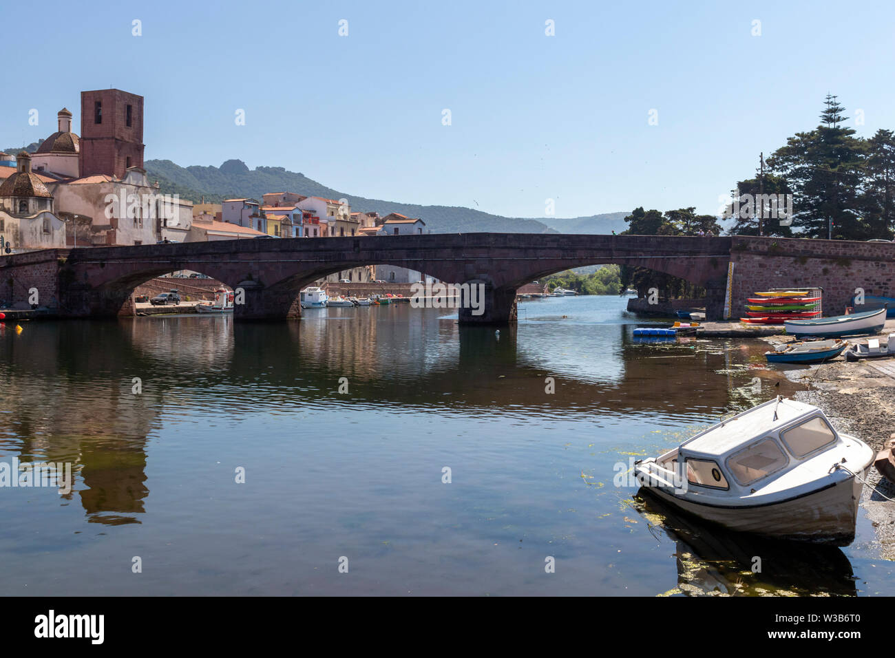 View of Bosa, Sardinia, with colorful Italian houses. River Temo with bridge and boat ashore in foreground. Summer day shot. Stock Photo